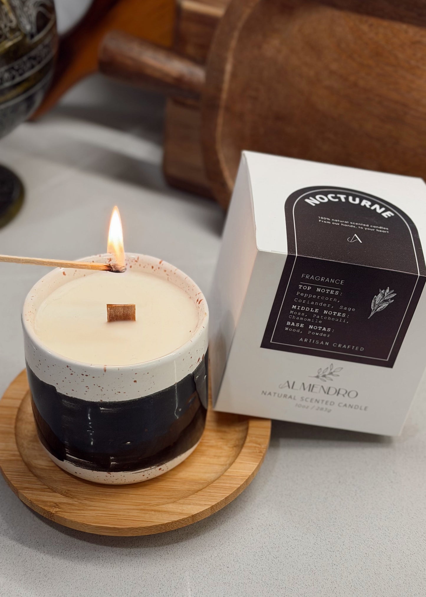 Candle with a wooden coaster and a box labeled 'Nocturne' on a gray surface